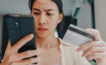 Personne manipulant son téléphone et sa carte bancaire